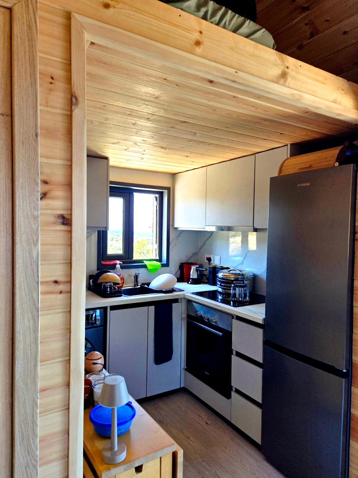Kitchen with wooden interior, black refrigerator, and white cabinets. Prefab house Cyprus. Prefabricated modular home Cyprus. Prefabcy. Buy modular home in Cyprus.