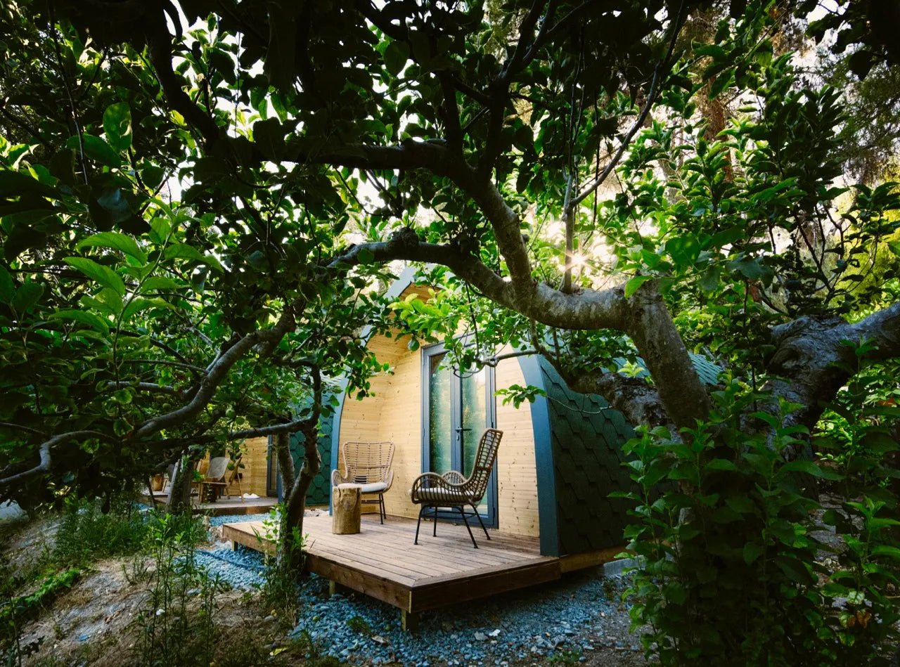 Small building with a wooden deck surrounded by lush greenery. Glamping in Cyprus. Prefab house Cyprus. Prefabricated modular home Cyprus. Prefabcy