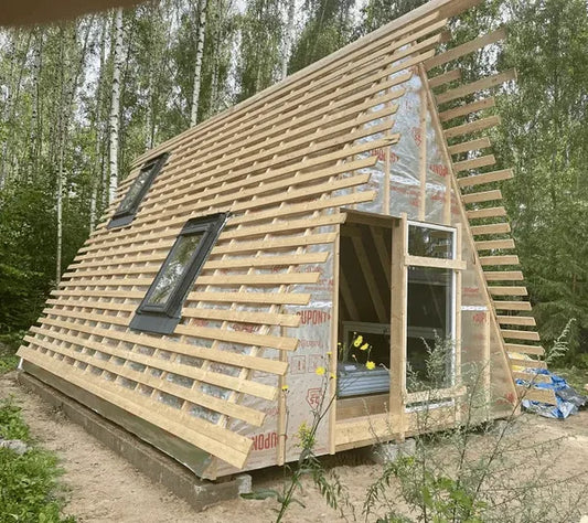 Wooden cabin A frame under construction with slanted roof and windows in a forest setting. Prefab house Cyprus. Prefabricated modular home Cyprus. Prefabcy
