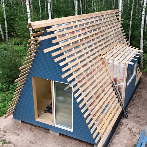 Small blue cabin with wooden exterior in a forest setting. Prefab house Cyprus. Prefabricated modular home Cyprus. Prefabcy